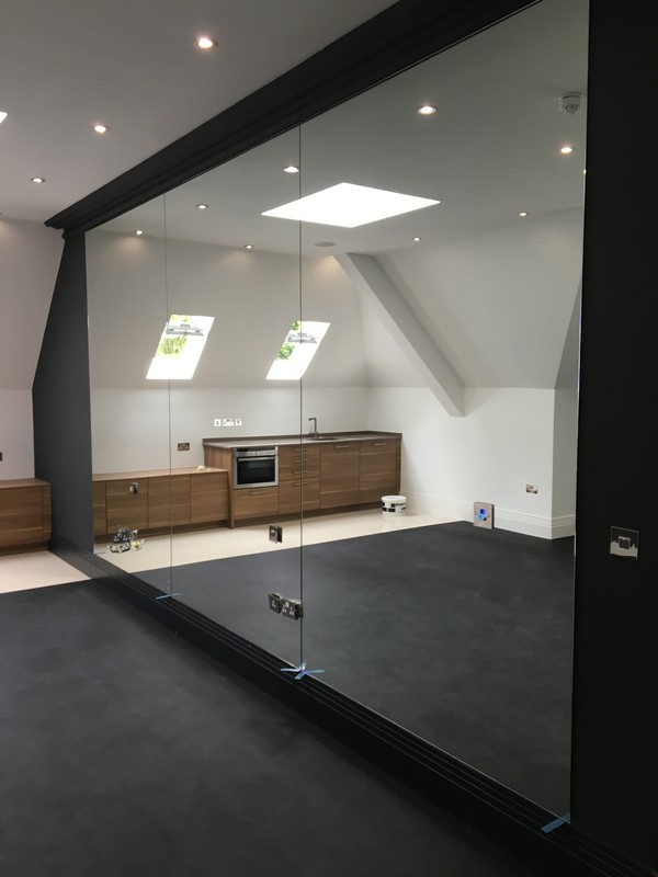 Frameless glass partition in loft conversion by Ealing glaziers